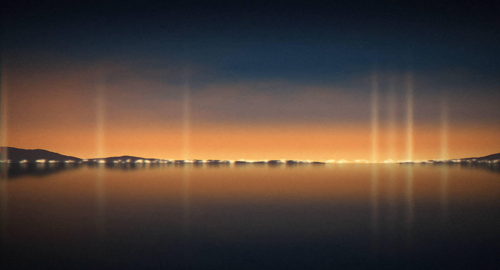 Sunset over calm water with city lights glowing on the horizon